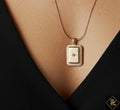 Gold necklace with a rectangular pendant on a black background