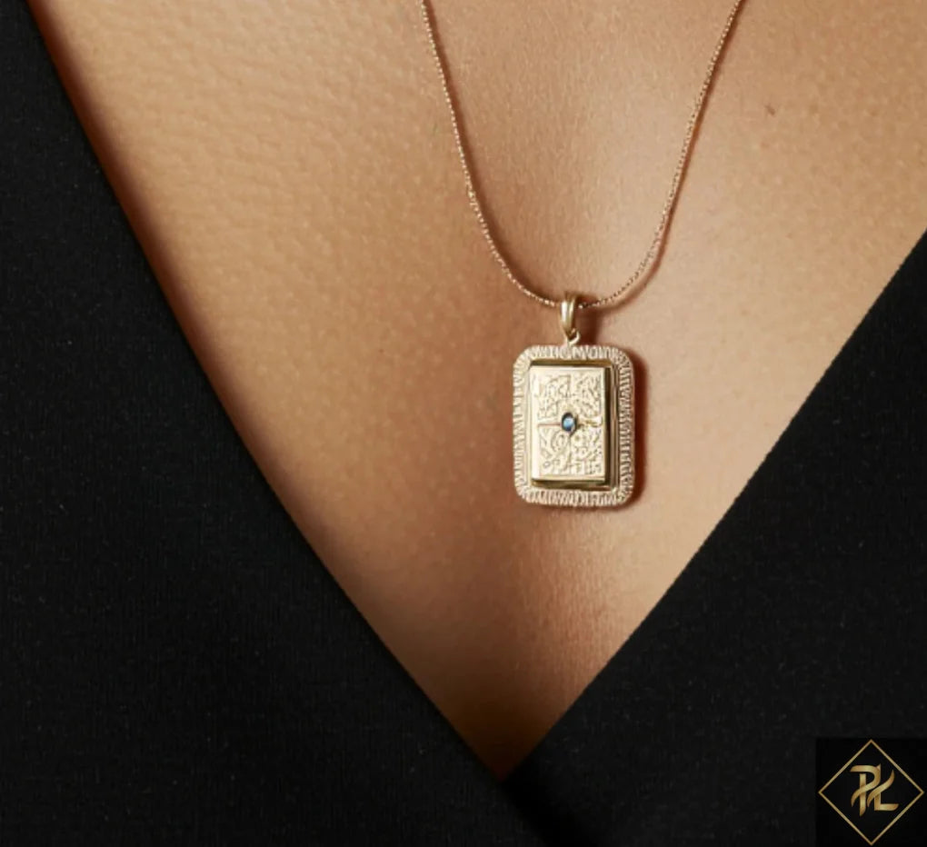 Gold necklace with a rectangular pendant on a black background