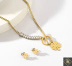 Gold necklace and earrings with a four-leaf clover charm on a white background
