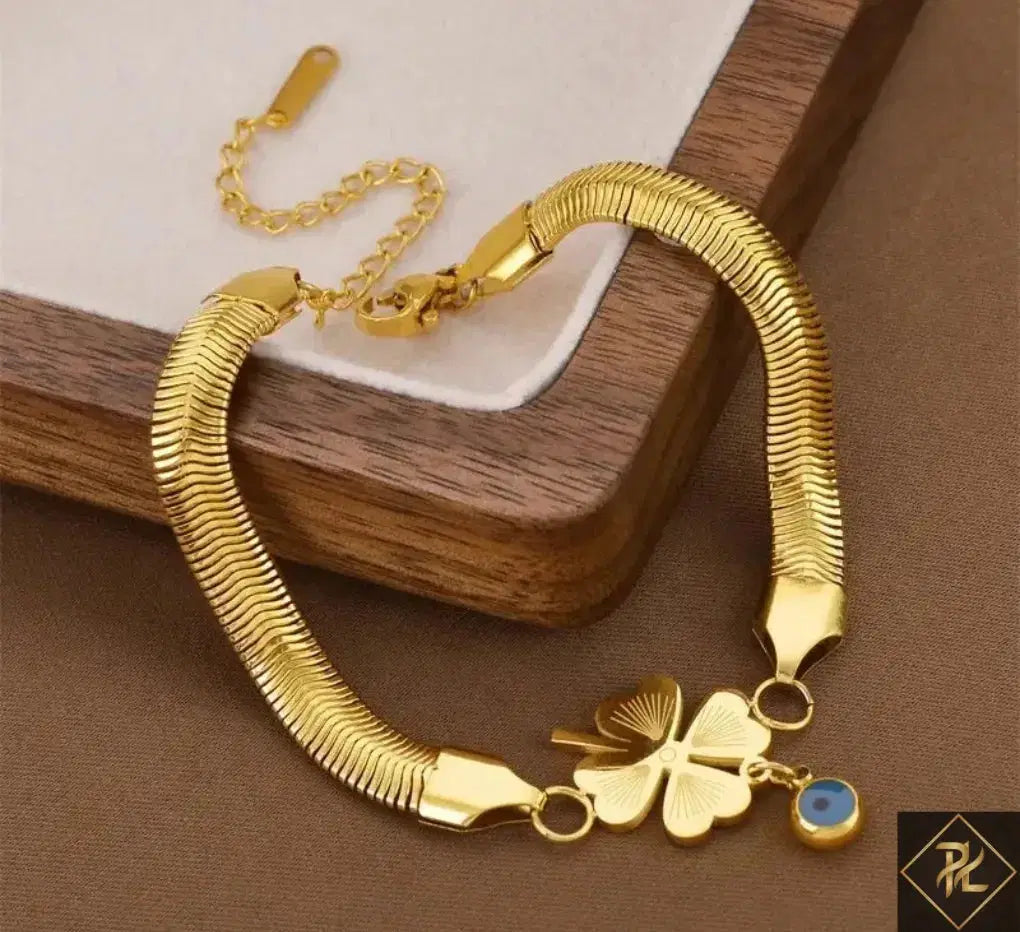 Gold bracelet with a clover charm on a wooden surface