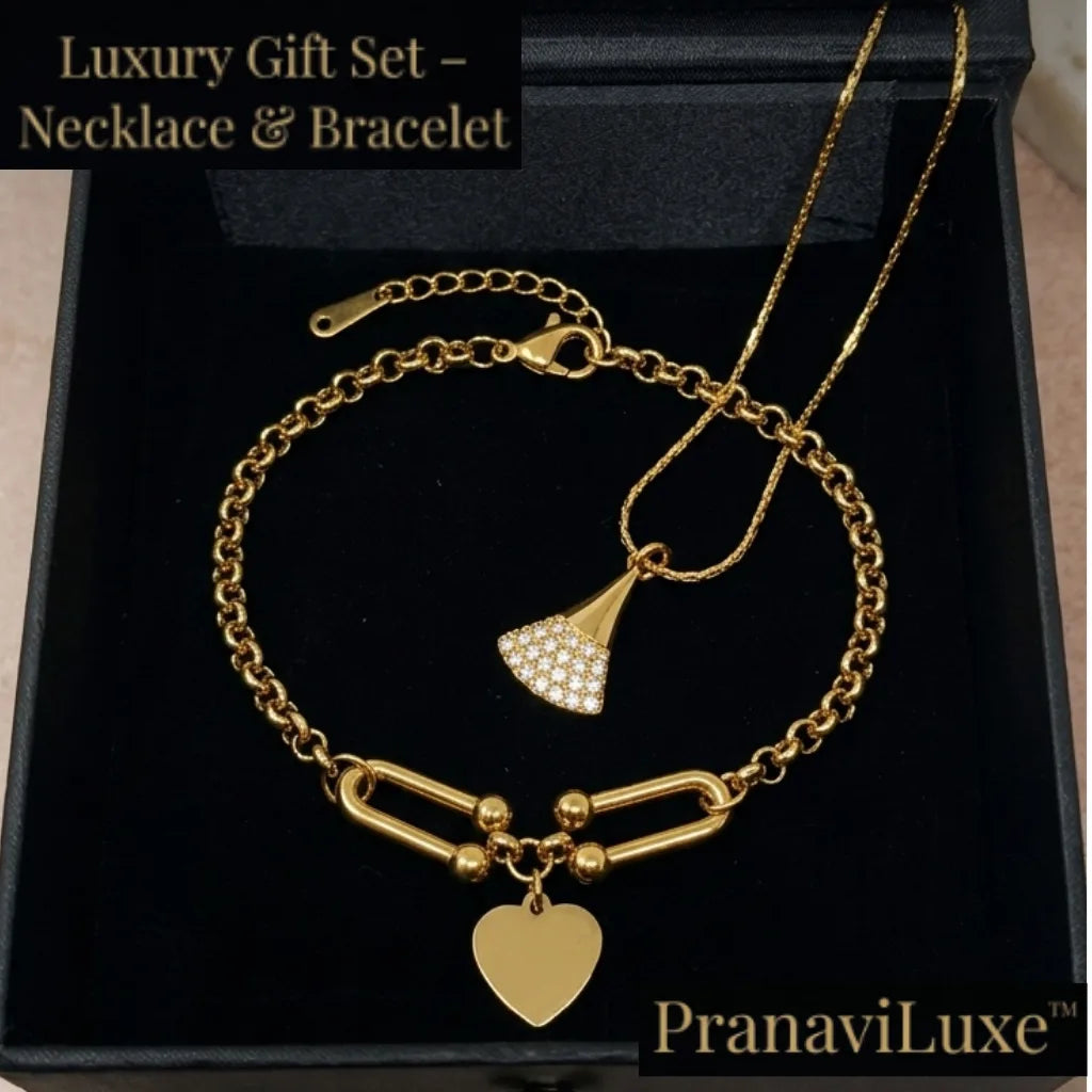 Gold necklace and bracelet gift set displayed on a black presentation box. The set includes a delicate gold chain necklace with a small pavé-fan pendant and a matching gold chain bracelet with a heart-shaped charm and bar-link detail.