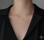 Gold necklace with a small pendant on a person wearing a black blazer.
