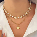 Necklace with starfish and pearl details on a person wearing a white top.