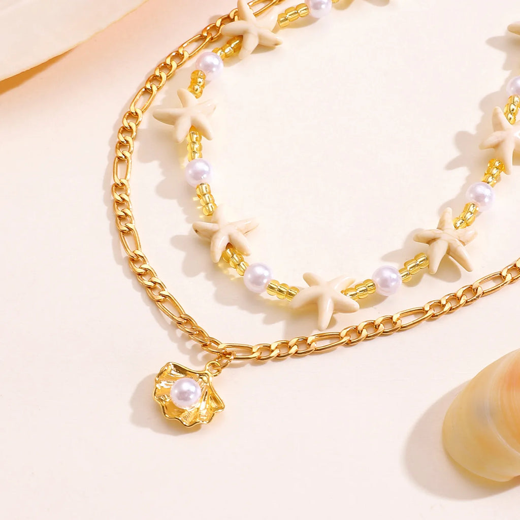 Gold chain bracelet with pearl accents on a light background