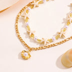 Gold chain bracelet with pearl accents on a light background