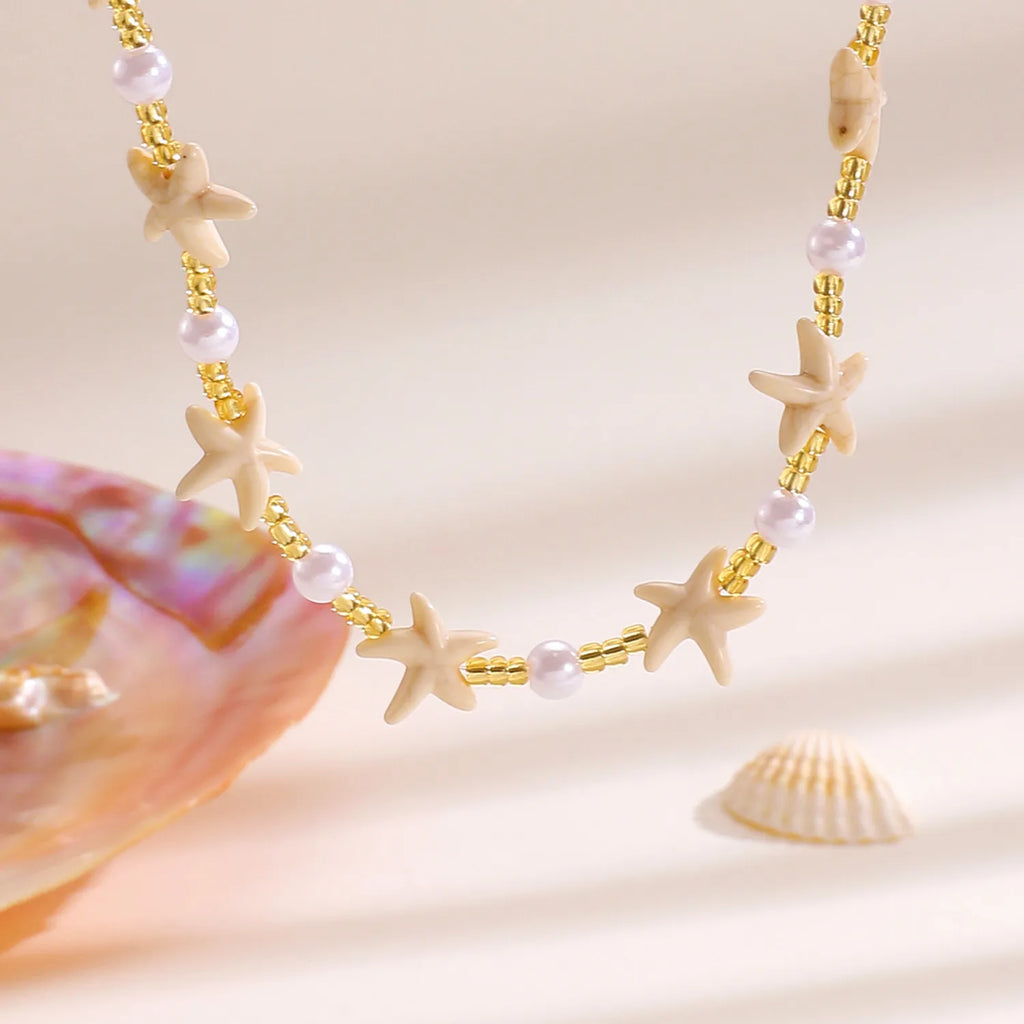 Necklace with starfish and pearl beads on a beige background