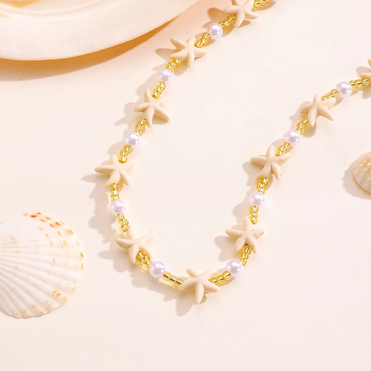 Necklace with starfish and pearl details on a beige background