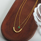 Green Stone Layered Necklace featuring a delicate gold-tone layered design with a small green stone pendant and geometric gold accents, perfect for elegant fashion accessories.