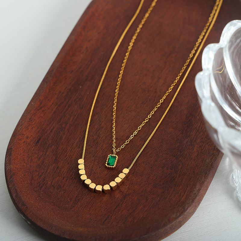 Green Stone Layered Necklace featuring a delicate gold-tone layered design with a small green stone pendant and geometric gold accents, perfect for elegant fashion accessories.