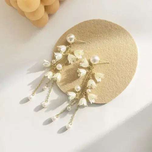 Long Flower Tassel Jewelry Earring featuring delicate white flower charms and pearl accents suspended from gold chains, perfect for elegant and trendy fashion jewelry looks.