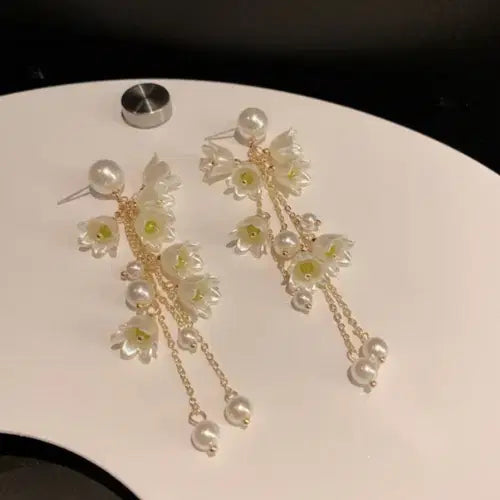 Delicate Long Flower Tassel Jewelry Earring featuring white floral accents and cascading pearl tassels on gold chains, perfect for elegant and stylish fashion jewelry looks.