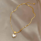 Elegant gold chain necklace featuring a Love Heart Shaped Pearl Pendant Necklace with a smooth, lustrous pearl heart charm against a silky beige background.