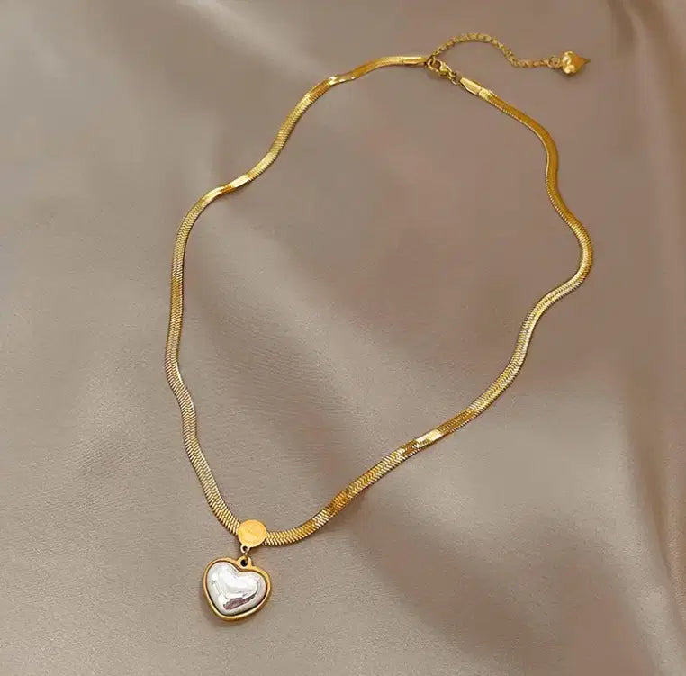 Elegant gold chain necklace featuring a Love Heart Shaped Pearl Pendant Necklace with a smooth, lustrous pearl heart charm against a silky beige background.