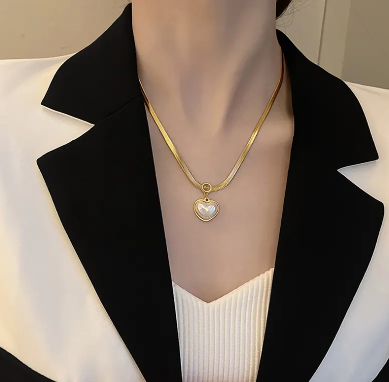 Mannequin wearing a black blazer and white shirt with a gold necklace featuring a heart-shaped pendant.