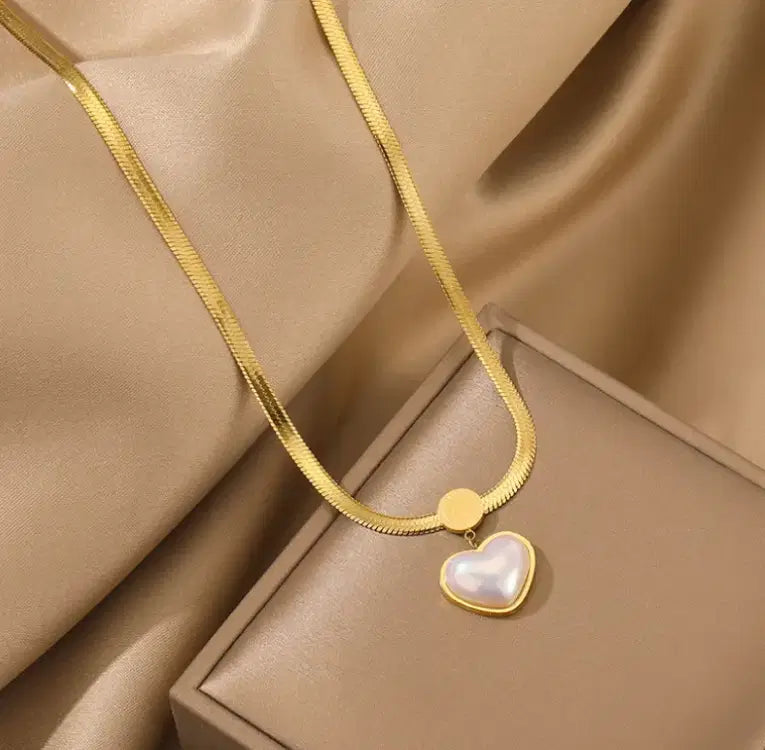 Love Heart Shaped Pearl Pendant Necklace featuring a gold-toned chain with a pearl heart-shaped pendant, displayed on a silky beige fabric and elegant jewelry box backdrop.