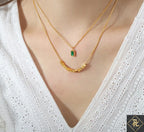 Close-up of a person wearing the Green Stone Layered Necklace featuring a gold chain with a small green rectangular stone pendant and a second gold chain with small gold beads, styled with a white textured blouse.