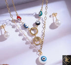 Gold necklace with eye-shaped beads and matching earrings on a white background