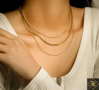 Close-up of a person wearing a Gold Plated Three-Layer Snake Chain Necklace, featuring three delicate gold-plated layers resting elegantly on the neckline paired with a white ribbed top.