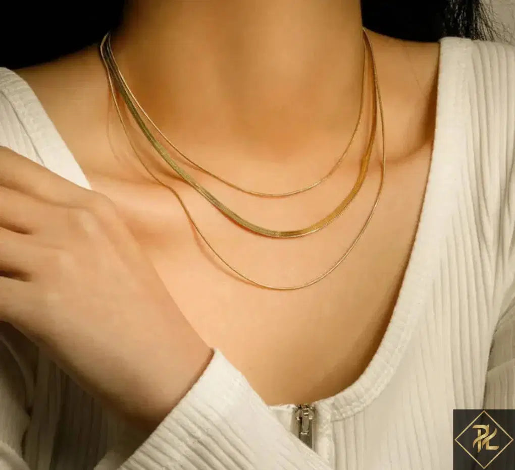 Close-up of a person wearing a Gold Plated Three-Layer Snake Chain Necklace, featuring three delicate gold-plated layers resting elegantly on the neckline paired with a white ribbed top.