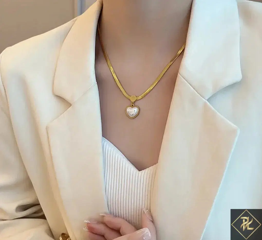 Woman wearing a gold chain with a Love Heart Shaped Pearl Pendant Necklace over a white top and cream blazer, showcasing elegant and minimalist fashion jewelry.