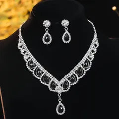 Silver necklace and earrings set on a black stand with blurred background