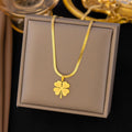 Gold necklace with a four-leaf clover pendant on a gray display box.