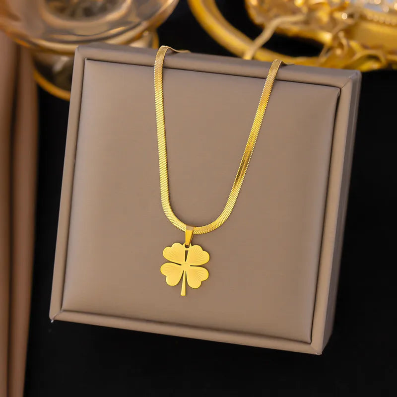 Gold necklace with a four-leaf clover pendant on a gray display box.