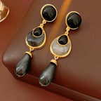 Gold earrings with black stones on a brown surface