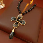 Decorative necklace with a black and gold pendant on a brown surface