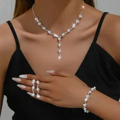 Woman wearing a pearl necklace, bracelet, and ring on a plain background