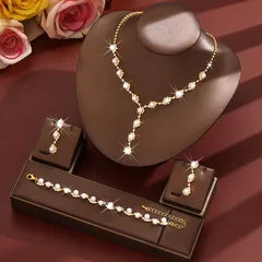 Necklace and earrings set on a brown stand with flowers in the background