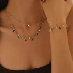 Gold necklace and bracelet with blue stones on a person's neck and wrist.