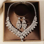 Silver necklace and earrings set in a brown box on a beige background