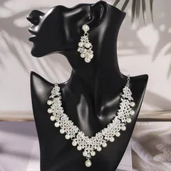 Pearl necklace and earrings on a black mannequin bust with a soft background