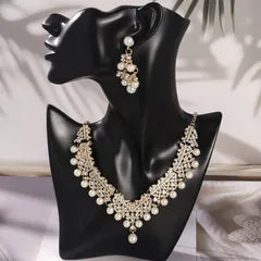Set of pearl necklace and earrings on a black stand with a blurred background