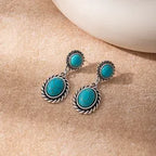 Pair of turquoise earrings on a beige surface