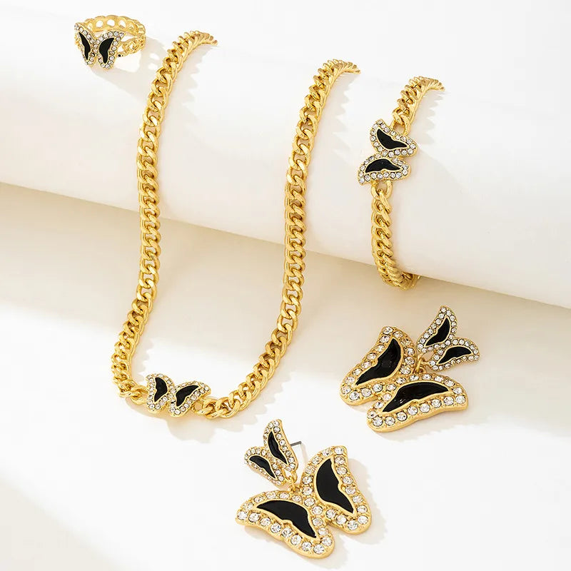 Gold chain necklace and butterfly earrings on a white surface