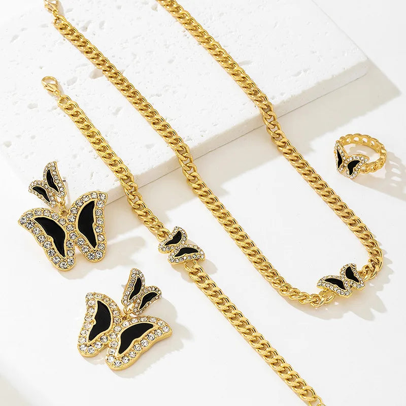 Gold chain necklace with black butterfly earrings on a white background