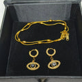 Gold-tone jewelry set including a beaded chain necklace and matching hoop earrings with evil eye charms, displayed in a black presentation box.