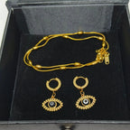 Gold-tone jewelry set including a beaded chain necklace and matching hoop earrings with evil eye charms, displayed in a black presentation box.