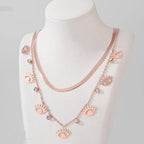 Rose gold necklace with eye-shaped charms on a mannequin against a gray background