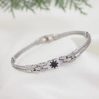 Silver bracelet with a black heart charm on a white background