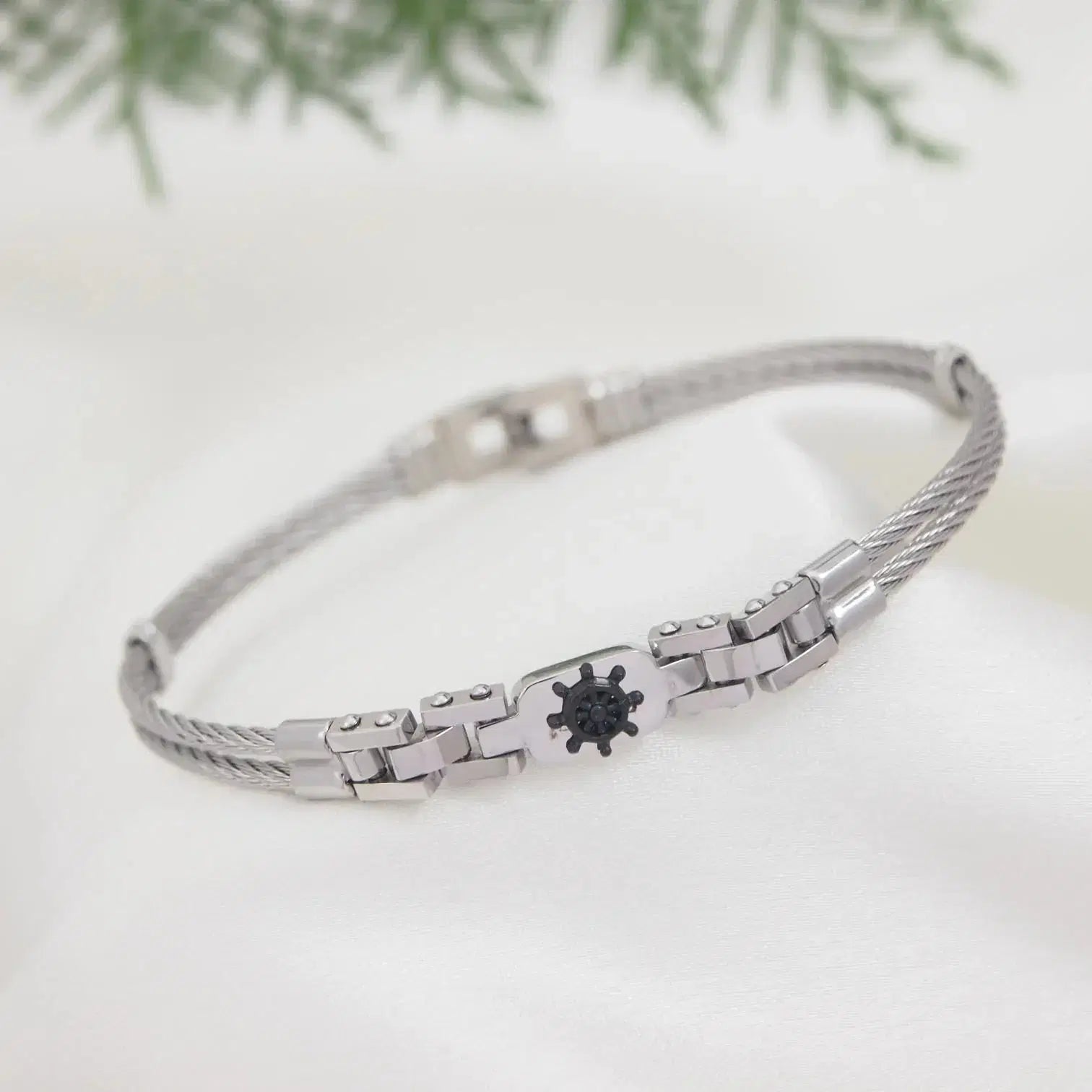 Silver bracelet with a black heart charm on a white background