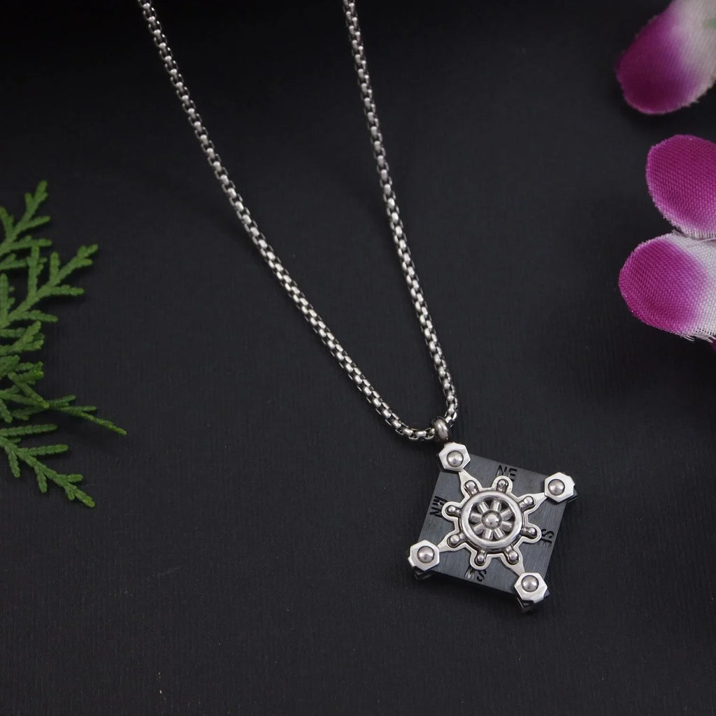Silver necklace with a detailed pendant on a dark background