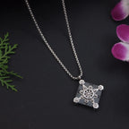 Silver necklace with a detailed pendant on a dark background