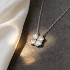 Silver necklace with a four-leaf clover pendant on a textured surface