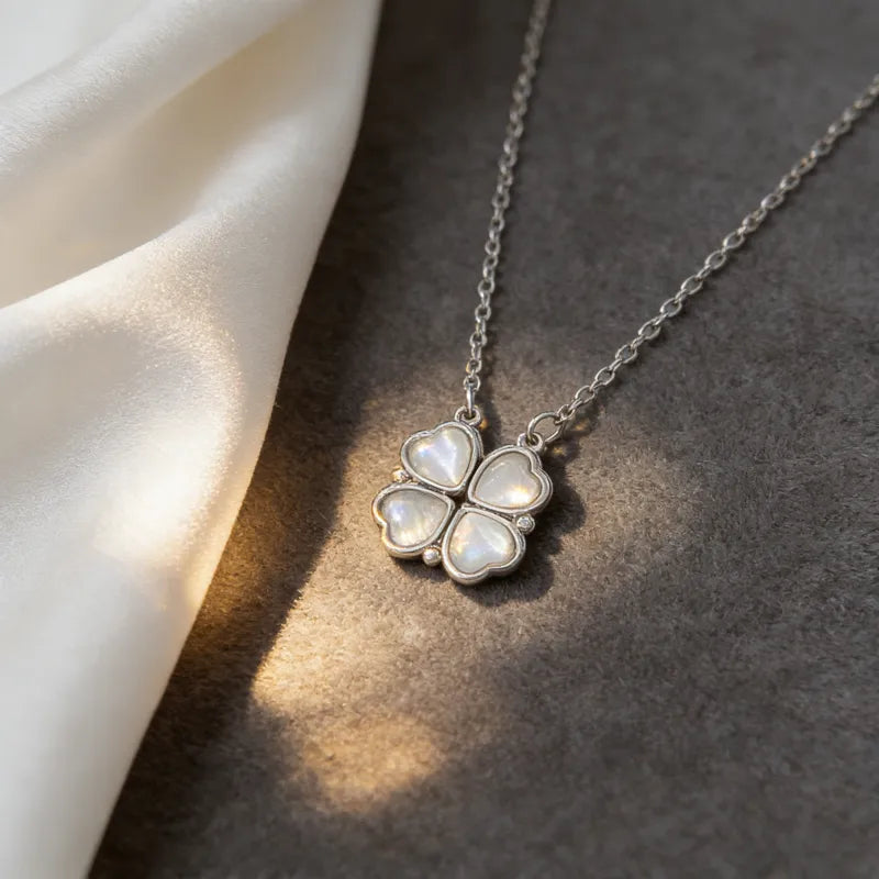 Silver necklace with a four-leaf clover pendant on a textured surface