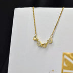 Gold necklace with heart-shaped pendants on a white box