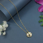 Gold necklace with a clover-shaped pendant on a blue background with flowers.