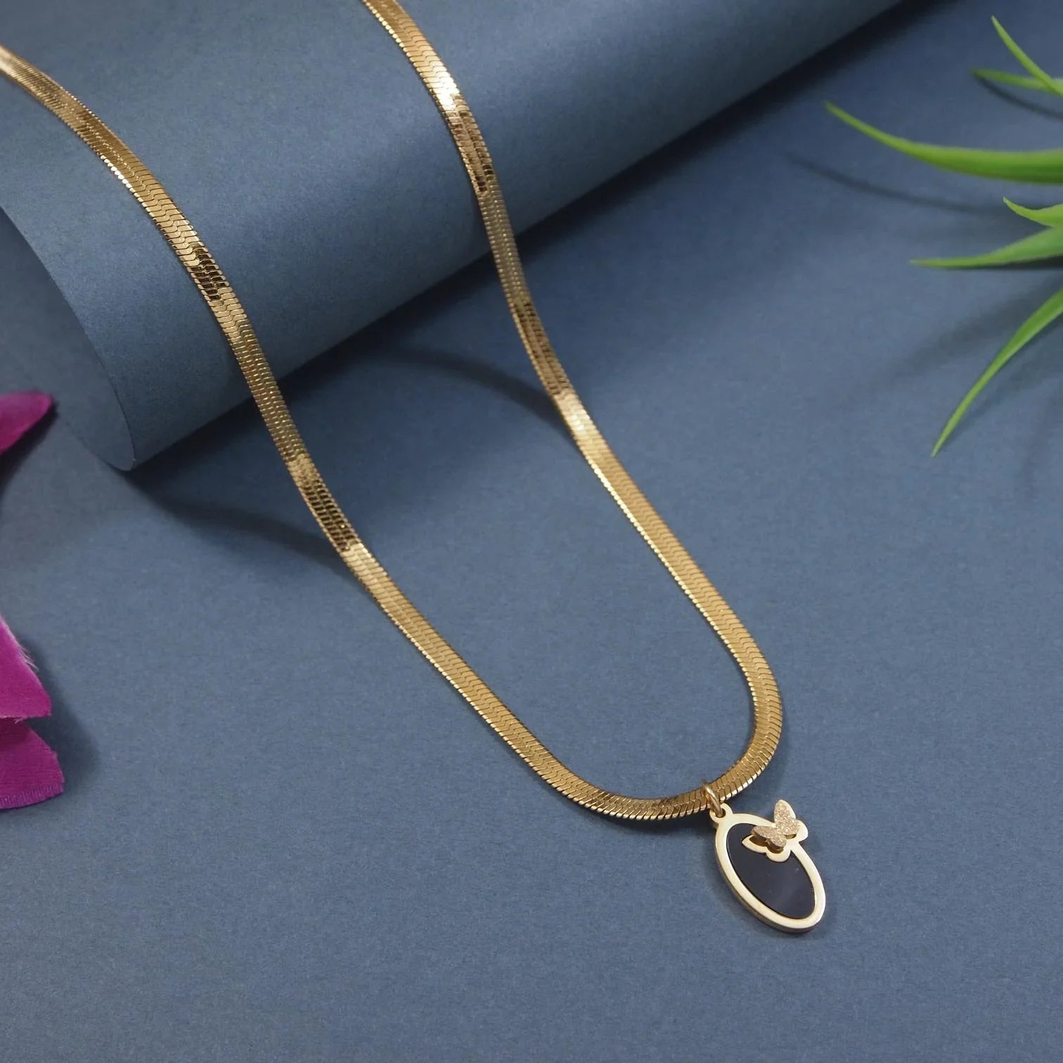 Gold necklace with a pendant on a blue surface